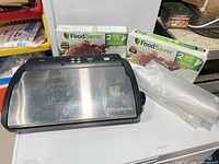 FoodSaver V2840 vacuum sealer with two boxed rolls and loose roll