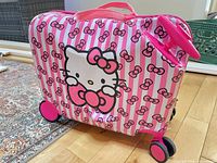 Front view of Hello Kitty striped hard-shell suitcase showing graphic, wheels and top webbing handle