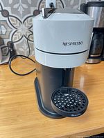 Front angled view showing Nespresso branding, head, drip tray, power cord