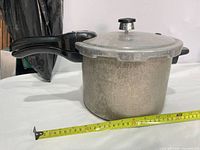 Side view of Presto aluminum pressure cooker showing body, lid and handles with measuring tape for scale