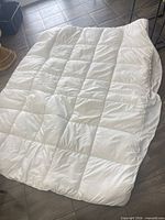 Full view of white quilted queen mattress pad laid flat