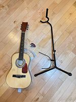 Overall view of guitar with strap, tuner and stand