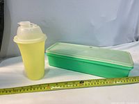 Shaker cup and container side by side with ruler for scale