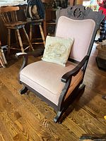 Front angled view of wooden rocking chair with embroidered pillow