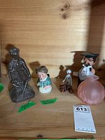 All five items grouped on shelf: metal monkey, Royal Doulton figurine, jointed doll, graduate figure, pink perfume bottle