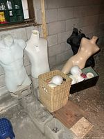 Group of two light grey torsos, wicker hamper with styrofoam heads, wooden bin, beige and black torsos partly visible