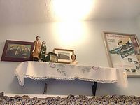 Shelf displaying framed photo, ceramic couple, small Queen Elizabeth II bust, framed Westinghouse irons poster