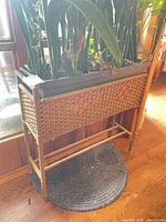Full view of woven wood planter on stand with live plants