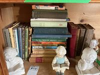 Shelf with mixed vintage books and three chalkware figures