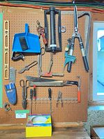 Wide view of pegboard showing most tools including plane, spokeshave, hedge shears, sprinkler, level, dustpan, screwdrivers