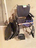 Wheelchair folded with cushions stacked alongside