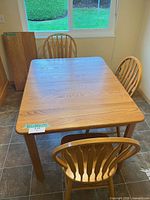 Top view of oak table with three chairs and leaf visible against wall