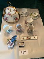 All twelve pieces laid out including cake stand, teacups, saucers, mugs, tray, trinket box and figurine