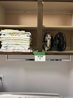 Shelf view showing folded linens stack and two vintage irons