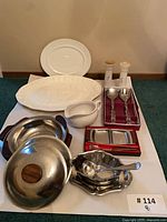 overview of lot showing ceramic platters, stainless dishes, utensils, condiment trays, bowls