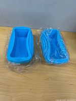 Two stacks of blue silicone loaf molds on table, one still wrapped