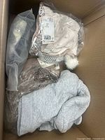 Top view of box showing grey hoodie and packaged pink infant clothes
