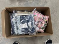 Box containing various clear-bagged clothing items
