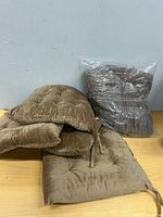 Brown slipcover sealed in plastic next to folded brown tufted cushions