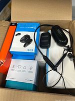 Overview of open box showing E7S earbuds box, black earphones, other boxed device