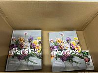 Open box showing two Pansies books and additional small packaged garden item