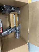 Overall view showing travel mugs, sealed carton, and other items in box