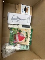 Top view of box showing kitchen scissors, Eggspoll package, boxed item with Asian text, mint green bottle, bubble-wrapped item