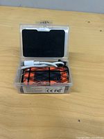 Box opened revealing orange device, wiring, USB cable