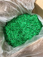 Open box with plastic liner showing large quantity of green dowel pins