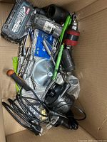 Top view of cardboard box containing Makita battery, sockets, pump and assorted tools