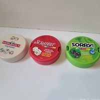 Front view of three round Express travel game cases: Monopoly, Scrabble, Sorry!