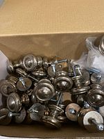 Box of numerous polished nickel-tone cabinet knobs with screws