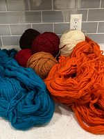 Assorted wool skeins and balls on countertop showing colour range and texture