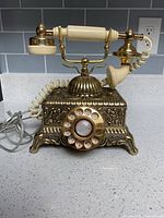Front view of ornate brass tone telephone with rotary dial