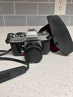 Front view of Ricoh Singlex II camera with lens cap and open leatherette case