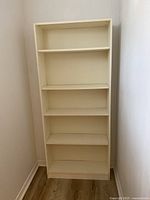 Full front view of tall white bookshelf with five shelf levels