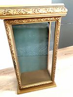 Front view of gilt wood display cabinet with glass door and green velvet backing