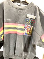 Front view of Adidas sweatshirt displaying stripes, Adidas logo, Olympic patch