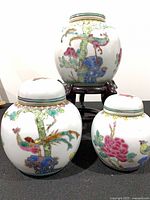 Front view of all three jars on stand showing painted motifs and relative sizes