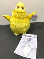 Front view of yellow Dance Along Boohbah plush with instruction manual
