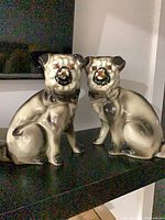 Front view of both large glossy porcelain pug figurines
