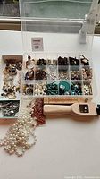 Overall lot showing organizer of beads, loose strands, leather strap cutter