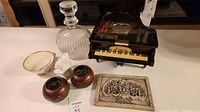 Group shot of all items: piano music box, decanter, teacup, rabbit figurine, two tealight holders, relief plaque