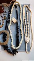 Overview of multiple necklaces, horn cuff, bone ring and other jewelry on cloth background