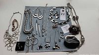 Full layout of all jewelry pieces on mat including necklaces, earrings, brooches, bracelet and coin purse