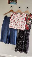 Three garments hanging: denim culottes, red-white crop top, floral dress