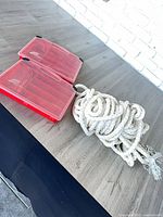Coiled white braided anchor rope and two red Plano tackle boxes on tabletop