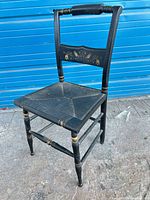 Full view of black wooden chair with gold accents