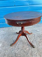 Full view of round pedestal table showing legs and brass claw feet