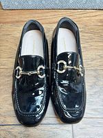 Top view of both black patent loafers showing gold horsebit hardware and overall condition